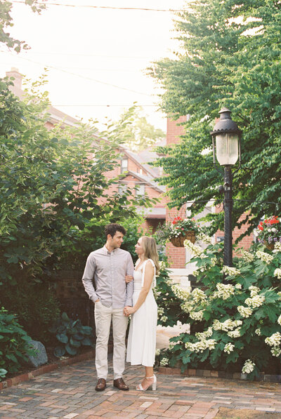 film photo of a couple looking at each other by a bush of hydrangeas and a lamp post, taken by Mansfield Wedding Photographer, Annie Trammel