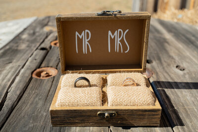 A close up of the bride and groom rings on top of a wooden barrel.