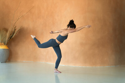 Sarah, a professional yoga teacher, in an embodied movement pose, captured mid-flow in a bright, thoughtfully styled space.