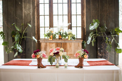 Floral centerpieces in boots on a rustic table