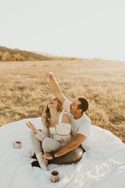 couple feeds each other popcorn at their picnic couples photoshoot