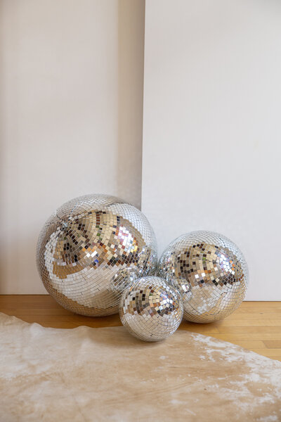 Three different size disco balls sitting on the floor.