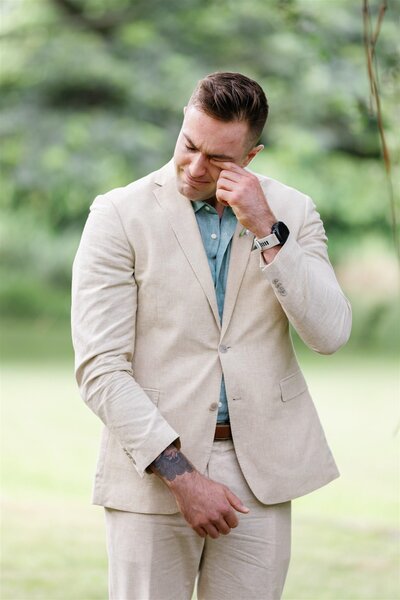 A person in a suit wiping a tear away during their wedding ceremony 