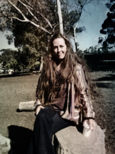 Sassy middle aged lady perched on a boulder with flowing hair and a cofffee cup in hand