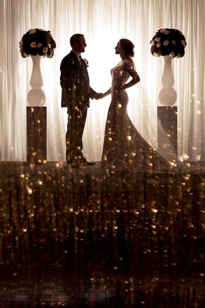 bride and groom holding hands while surrounded by sparkles