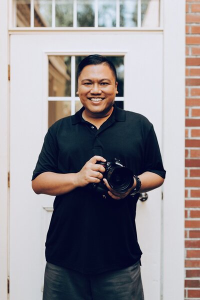 Photographer Jaymel Molina posing with a Nikon camera, smiling confidently.