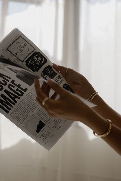 A woman's hands opening a newspaper