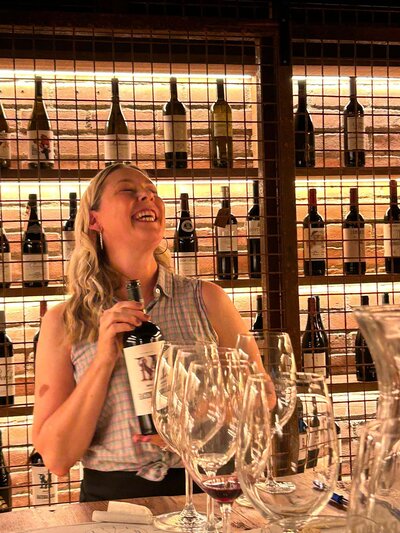 Wine Guide and expert Maria Cristina Barrero holding a wine bottle and laughing.