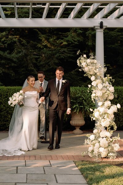 Gorgeous floral aisle markers with white roses and greenery by Leigh Florist, enhancing the charm of a wedding ceremony at Knowlton Mansion.