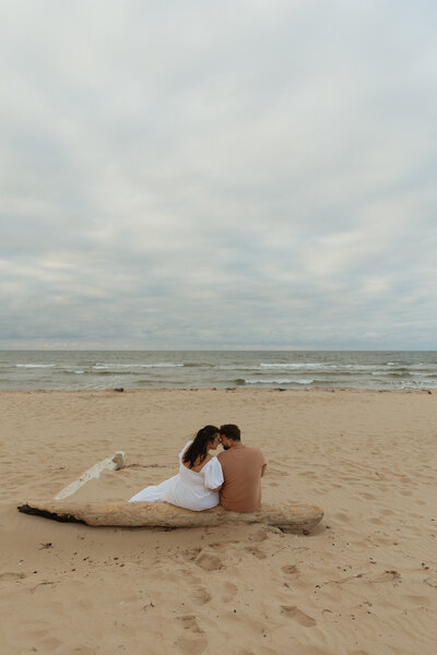 couple embrace on beach during engagement session on prince edward island