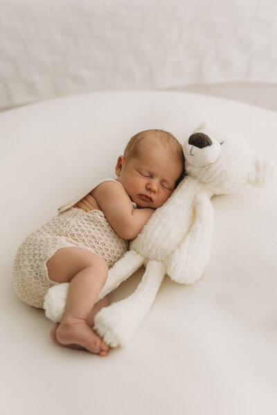 Cute baby cuddled up with a teddy bear