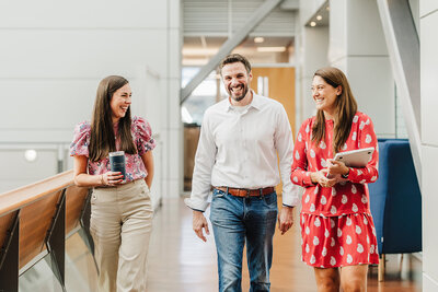 employees walk the hall and laugh in a modern boston workplace