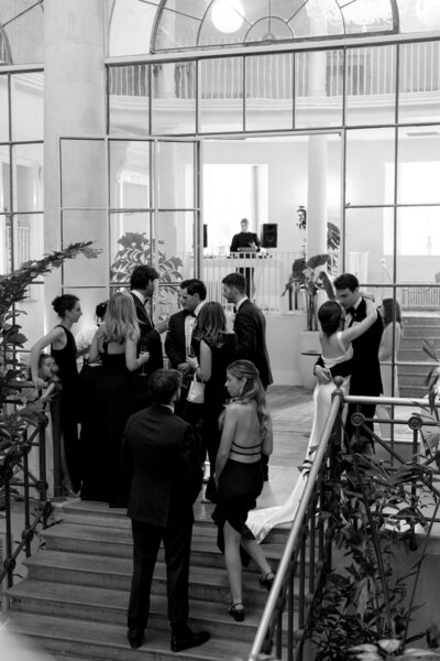 Stylish black-and-white shot of wedding guests arriving at the staircase for drinks reception.