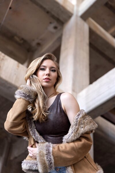 Senior girl in leaher jacket with fur collar looking down at camera