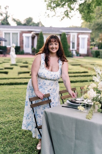 a woman in a blue and white dress standing at table 