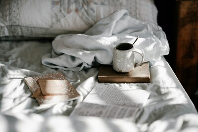 cozy morning bed with notebook and mug for hot drink