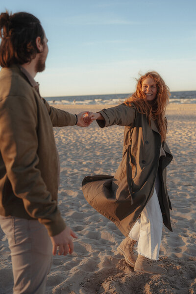 Paar bei goldenem Licht am Ostseestrand vor dem the breeze Hotel.