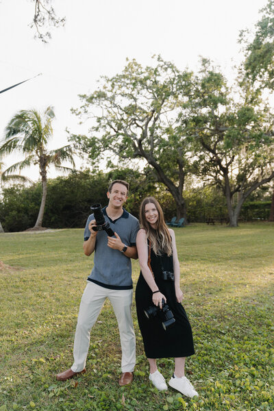 Male and Female Videographer pose with cameras