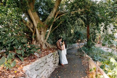 Engaged couple walking across a wooden bridge under the trees at Ferndell Trail in Los Angeles