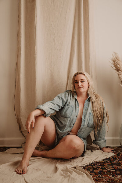 A person in a button down shirt sitting on the ground 