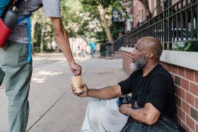 homeless man holding out a cup for donations