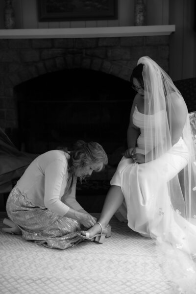 photo of mother helping her daughter put on her wedding shoes taken by maryland wedding photographer