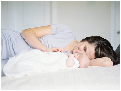 A new mother lays on her bed with her baby, photographed by Newborn Photographer Baltimore Marie Elizabeth Photography