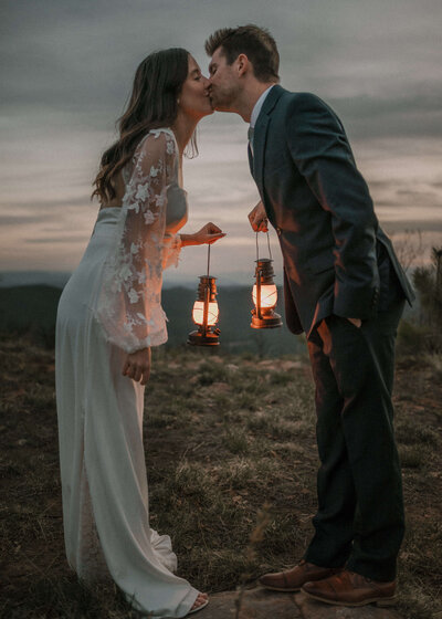Bride and Groom Kissing While Holding Lanterns