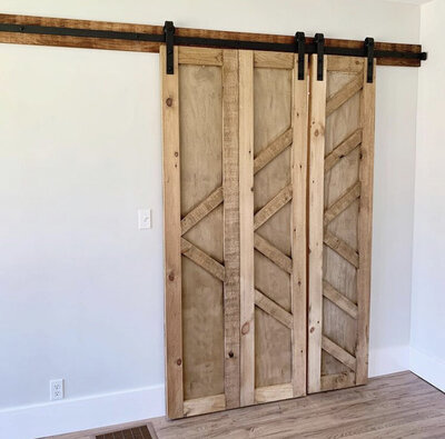 Natural wood barn door with geometric design hanging in home