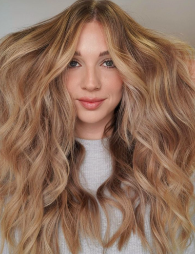 Woman with voluminous golden blonde waves, styled with balayage at Salon Beau for a dimensional look.