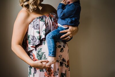 A pregnant woman holding a young child in a nurturing embrace, captured beautifully by a Pittsburgh maternity photographer.