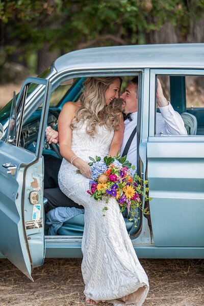 Newlyweds kissing in blue vintage car on elopement day