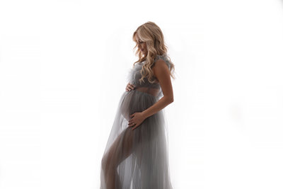 Pregnant woman wearing gray dress with white background photo taken by Southeast Michigan maternity photographer Kat Figlak