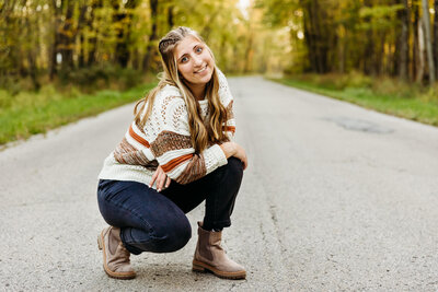 high school girl kneeling on a road for senior photo session