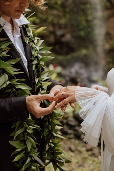 groom placing a ring onto brides finger