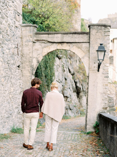 Couple walk hand in hand down stone walkway