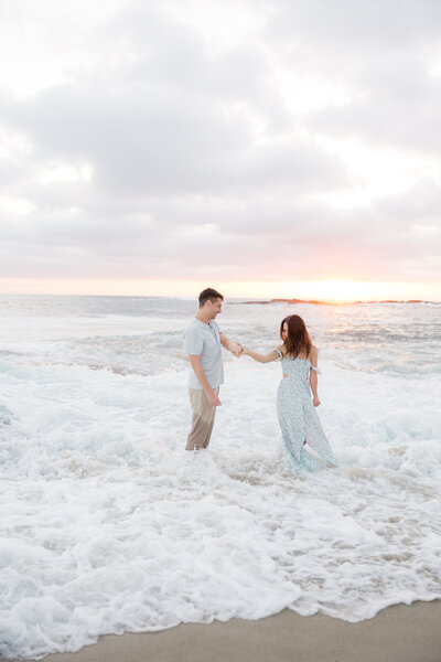 couple holding hands in ocean waves