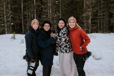 Two adventure elopement photographers standing next to two brides