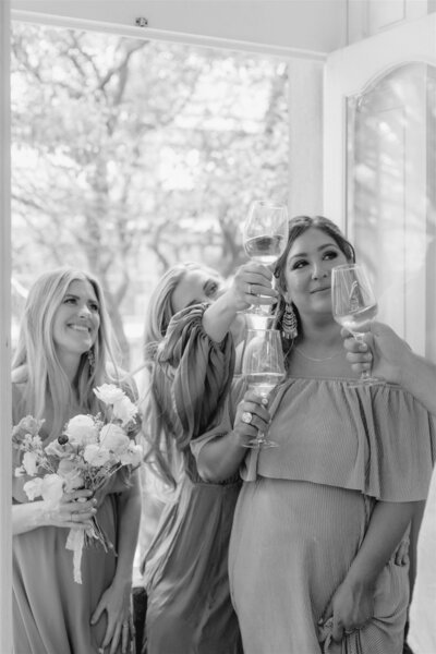 bridesmaids smiling holding bouquets and champagne glasses