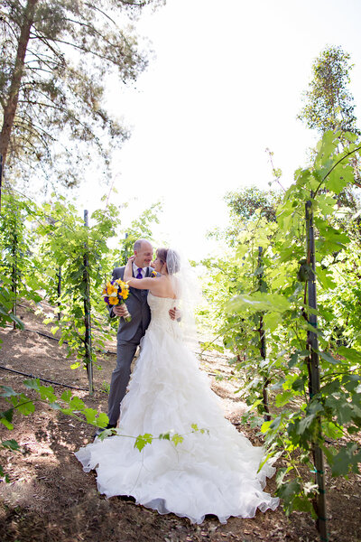Bride and Groom hugging with colorful florals at their wedding at Lake Oak Meadows