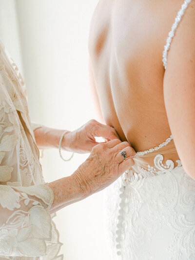 Older mother buttoning her daughter into her wedding gown photographed by Charlottesville Virginia Wedding Photographer Amanda Adams