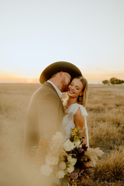 okc wedding photographer docuemnts groom kissing bride on the cheek