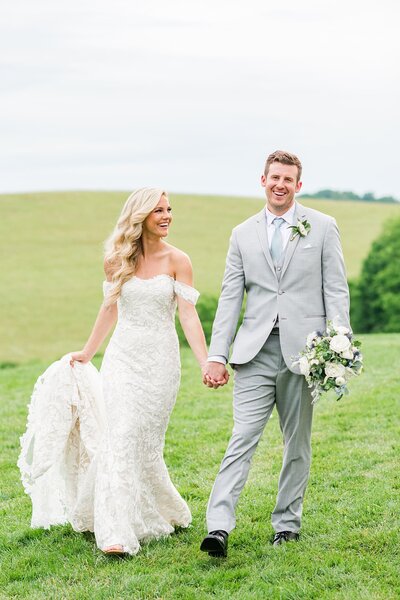 White Dove Barn wedding of bride and groom walking in field