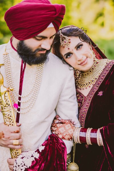 A sikh bride and groom in red outfits at natirar park bridgewater nj after their anand karaj wedding