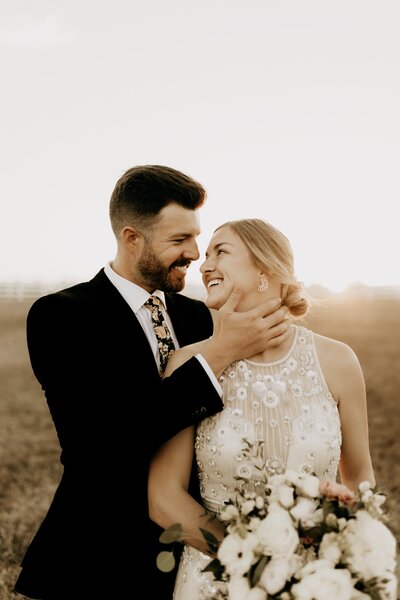 groom smiling and holding brides face