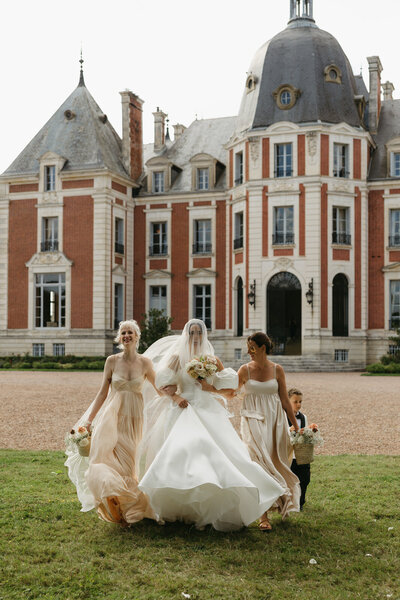 Bride with her sisters and ring bearer walking down the aisle to her cermeony with chateau Domaine du Réveillon in the backdrop of this beautiful fall wedding in Burgundy, France, documented by Andrea-Marie Photography
