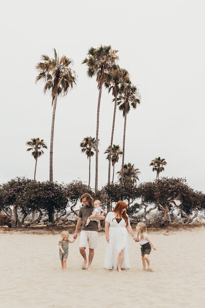 a family walks on mission beach while on vacation in san diego