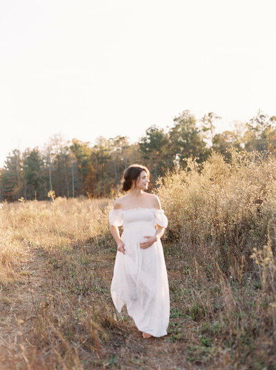 Maternity photography with mother wearing a white dress in an open field