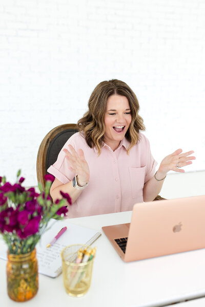 A dedicated women's healthcare specialist from Reforme Wellness consults with a patient using a pink laptop, emphasizing personalized and compassionate care. She is seated in front of a white desk.