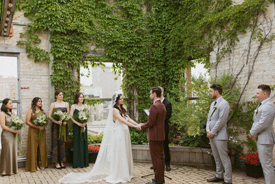 A romantic outdoor wedding ceremony at a castle-like venue, surrounded by vines and elegant architecture.